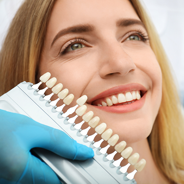 The image features a woman holding a dental implant device with a smile, showcasing her teeth.