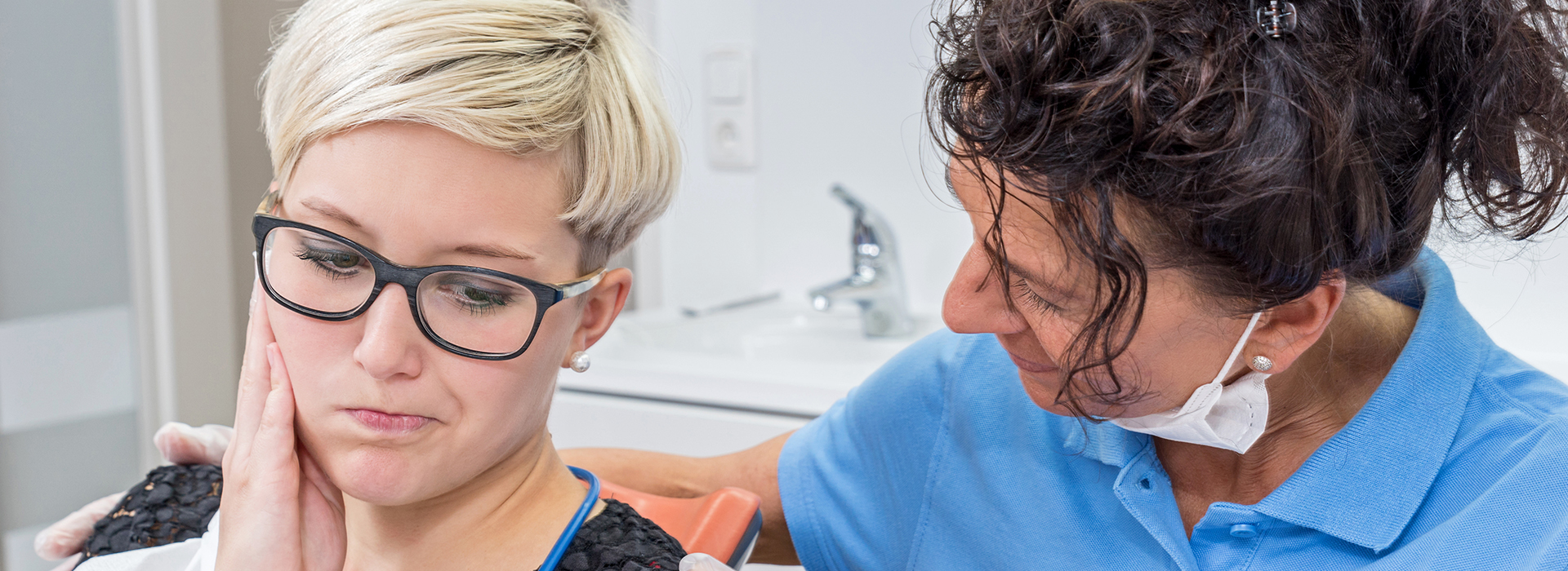 The image shows a person receiving dental care from a professional, with the focus on the interaction between them.