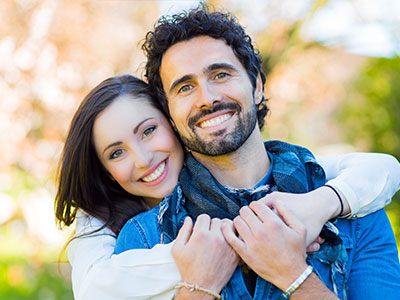 The image shows a man and woman embracing each other outdoors  they appear to be posing for a photo.