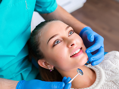 A woman receiving dental care with a hygienist assisting her.